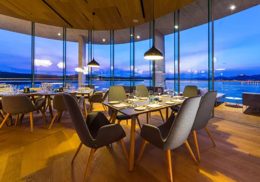 Dining area with large windows, looking out to a lake in the distance
