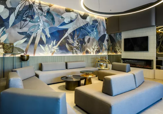 Seating area in front of a fireplace with blue flower paintings on the walls and gray couches