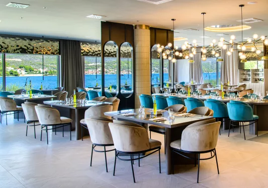 Dining hall in a restaurant with beige and teal chairs and marble tables