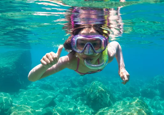 Girl scuba diving in the ocean, with her thumb up
