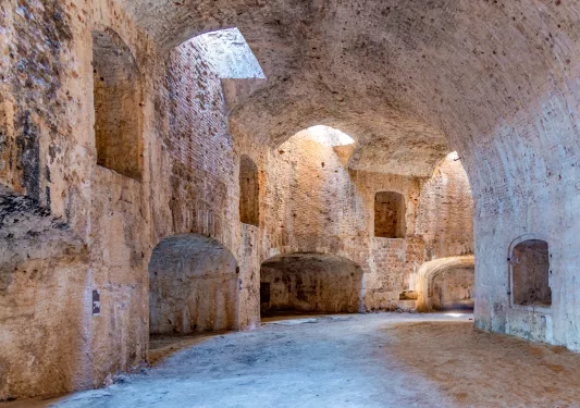 Large stone building ruins with sunlight peeking through the openings