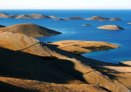 Large, dry hills with the ocean to the right