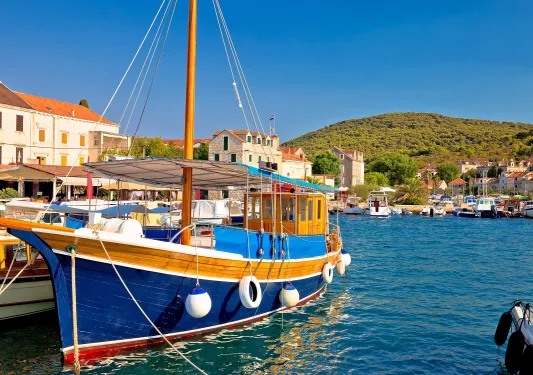 Blue and orange boat docked, with a small town in the background