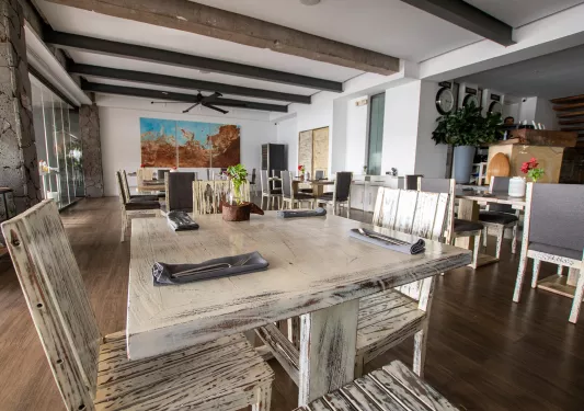 Indoor dining areas with white, wooden tables and chairs in a white room