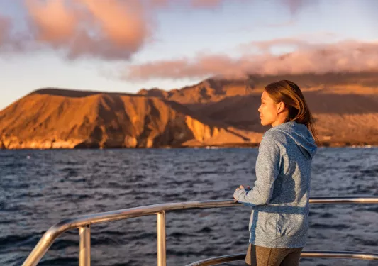 Woman standing on a boat, looking out to the ocean