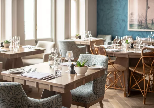 Dining room with wooden tables and clue, cushioned chairs