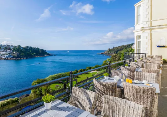Outdoor patio with woven chairs and the ocean to the left