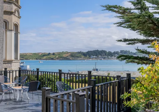 Outdoor patio with chairs and tables, looking out towards a large lake