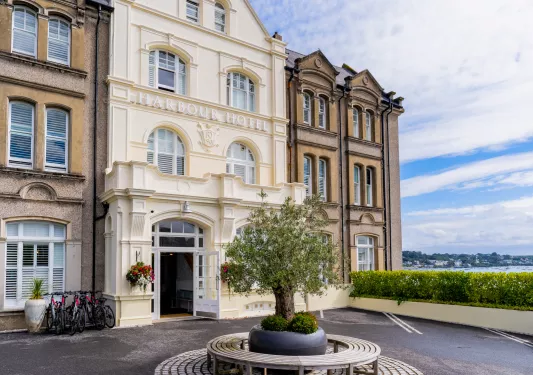 Exterior view of cream-colored building with an asphalt courtyard by the ocean
