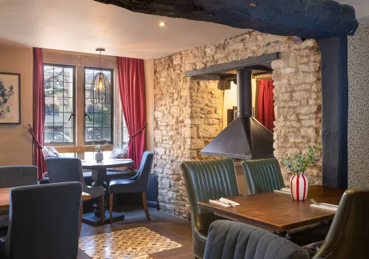 Restaurant with exposed brick walls and cushioned chairs surrounding square tables