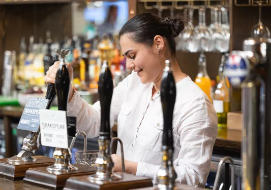 Bartender pouring a glass of beer while smiling