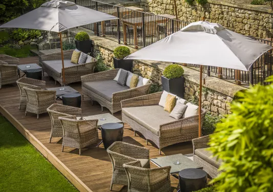 Outdoor patio with a wooden platform, cushioned chairs and white umbrellas
