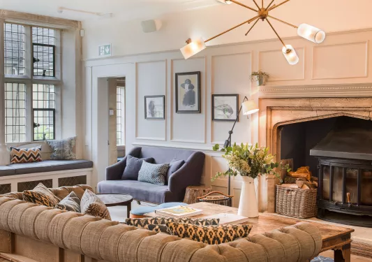 Indoor lounge with large, cushioned sofas in front of a stone fireplace