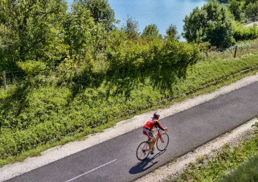 Person riding a bike on a road with a lake in the background
