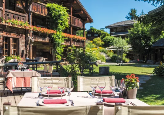 Dining table outdoors with two wooden lodges in the background