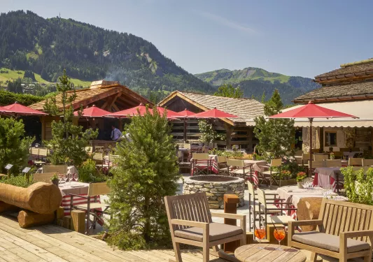 Outdoor patio with red umbrellas and wooden cabins in the background