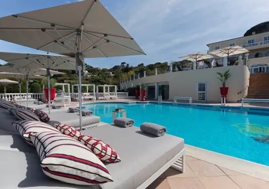 Outdoor pool surrounded by gray reclining chairs and white umbrellas