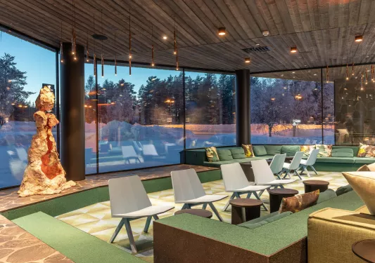 Hotel lobby with green furniture and cushioned chairs, with large windows