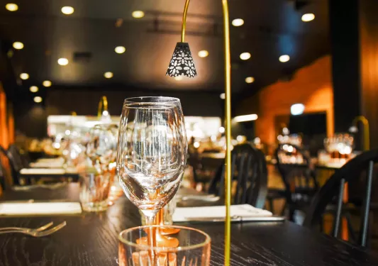 Black dining table with wine glasses and a small light fixture on top