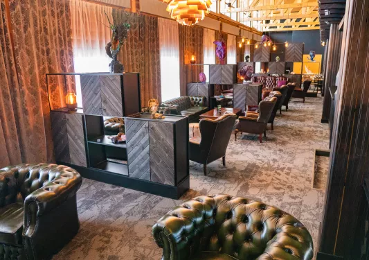 Long room with green leather couches and wooden coffee tables