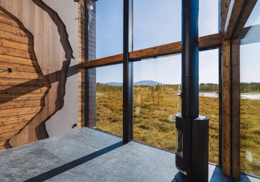 Corner of a large room with exposed wood walls and large windows