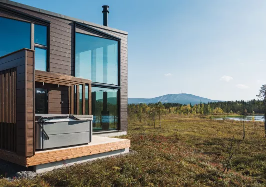 Exterior view of wooden building with large windows and a large valley in the back