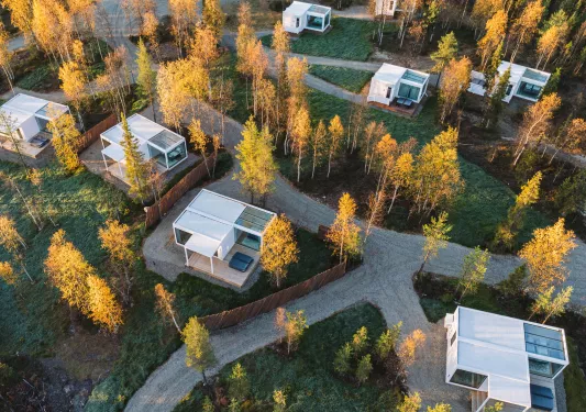 Sky view of white buildings in a valley with grass fields and yellow trees