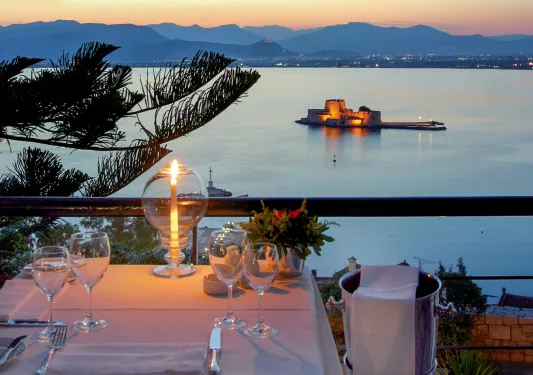 Outdoor patio with a dining table and wine glasses, with a view of a large lake