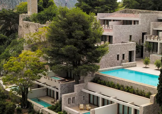 Exterior view of stone hotel building with mini outdoor pools