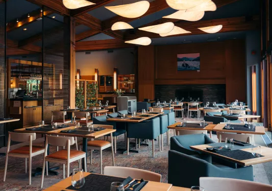 Restaurant dining hall with blue cushioned chairs in front of wooden dining tables