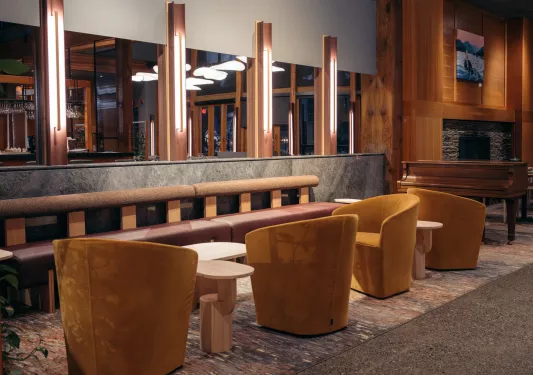 Hotel lobby seating area with cushioned chairs and illuminated, wooden pillars