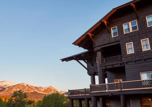 Exterior view of dark brown lodge building with mountains in the distance