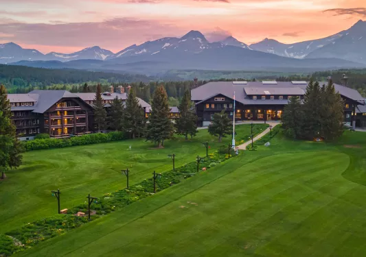 Large grass field in front of two large, dark brown hotel buildings