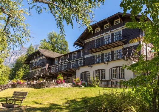 Exterior view of cabin-styled hotel building with a garden and staircase in front