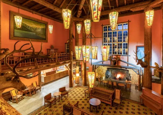 Lodge-style hotel lobby with large light fixtures and a fireplace on the ground floor