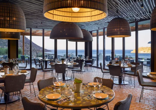 Dining hall with circular tables and woven chairs, with woven light fixtures