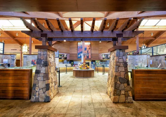 Indoor dining hall with food counters and a large stone archway