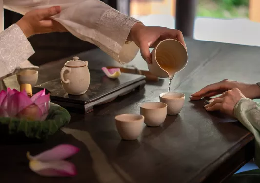 Person pouring tea into three tea cups