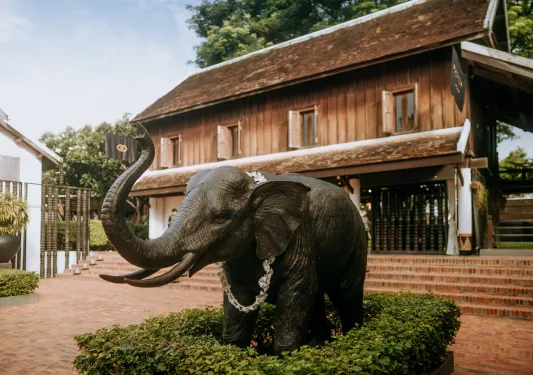 Exterior view of brown house with a bronze elephant statue in front