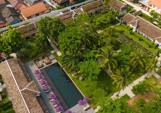 Sky view of outdoor pool and garden surrounded by tall trees