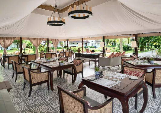 Outdoor dining area with large tent covering leading to a forest in the back
