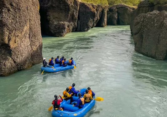 Two blue rafts on a river full of groups of people