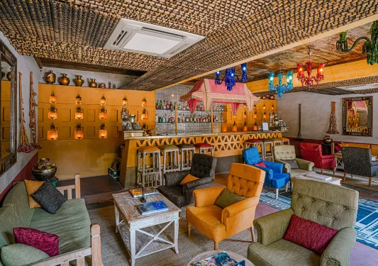 Indoor bar and lounge with cushioned sofas and colorful light fixtures