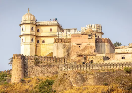 Rustic, stone building with people standing at the top of the roof