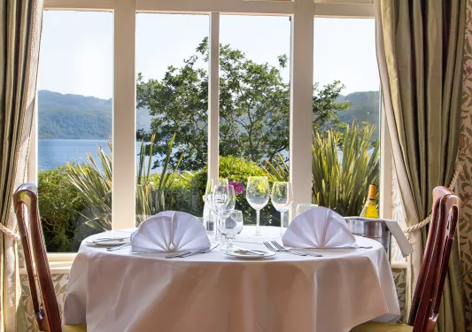 Circular dining table with wine glasses, next to a large opened window
