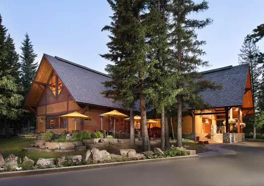 Exterior view of large wooden cabin, surrounded by tall trees