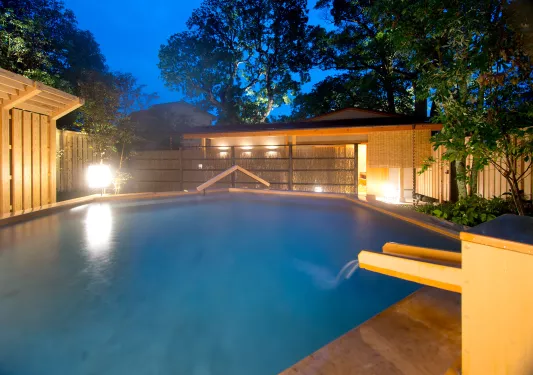 Outdoor sauna and open bath, surrounded by tall trees
