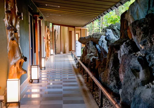 Outdoor walkway surrounded by sculpted wooden statues and large boulders