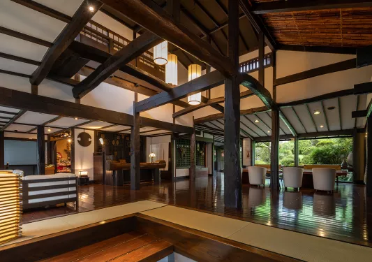 Indoor hotel lobby with large wooden pillars and gray chairs in he back