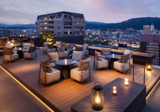 Hotel rooftop deck with cushioned chairs and circular tables